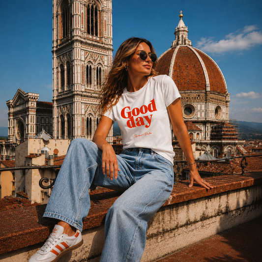 Woman sitting on a rooftop in Florence Italy with the duomo in the background wearing a Spiritual lifter t shirt with graphic "Good Day" and jeans.