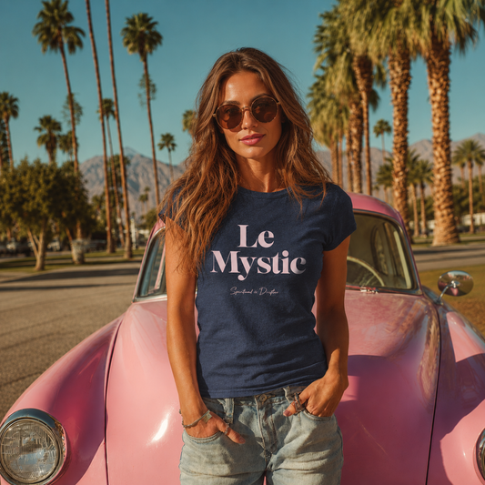 Woman wearing the Spiritual Drifter 'Le Mystic' t-shirt in front of a pink vintage car with palm trees and mountains in the background. Conscious clothing for alchemists. mystics and spiritual seekers.