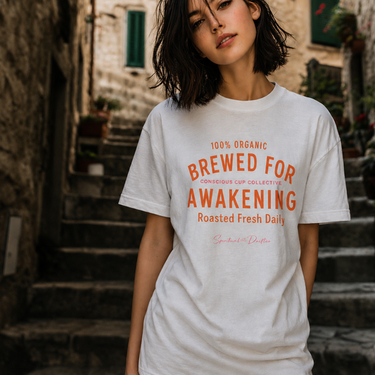 Woman wearing oversized Spiritual Drifter Brewed for Awakening coffee graphic organic cotton t-shirt in white with orange text. Spiritual lifestyle, positive vibes, aligned, positive mindset, conscious living clothing.