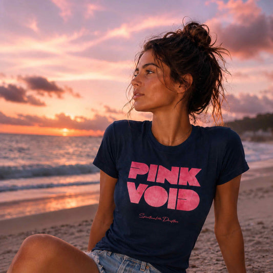 Woman wearing a 'Pink Void' t-shirt on a beach at sunset