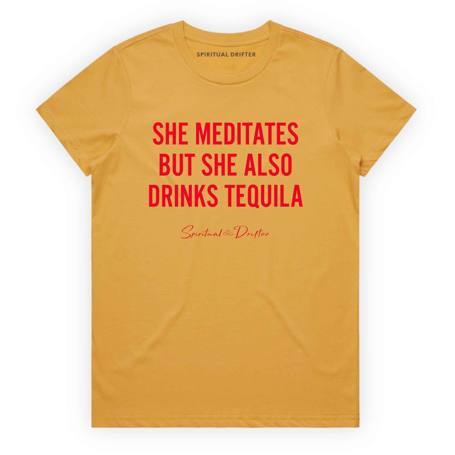 Mustard yellow Spiritual Drifter t-shirt with red text 'SHE MEDITATES BUT SHE ALSO DRINKS TEQUILA' on a white background. Women's spiritual graphic tee. Relaxed beach lifestyle fashion for meditation lovers, yoga enthusiasts, wellness travelers, and free-spirited women. Meditation and yoga clothing for awakened souls.