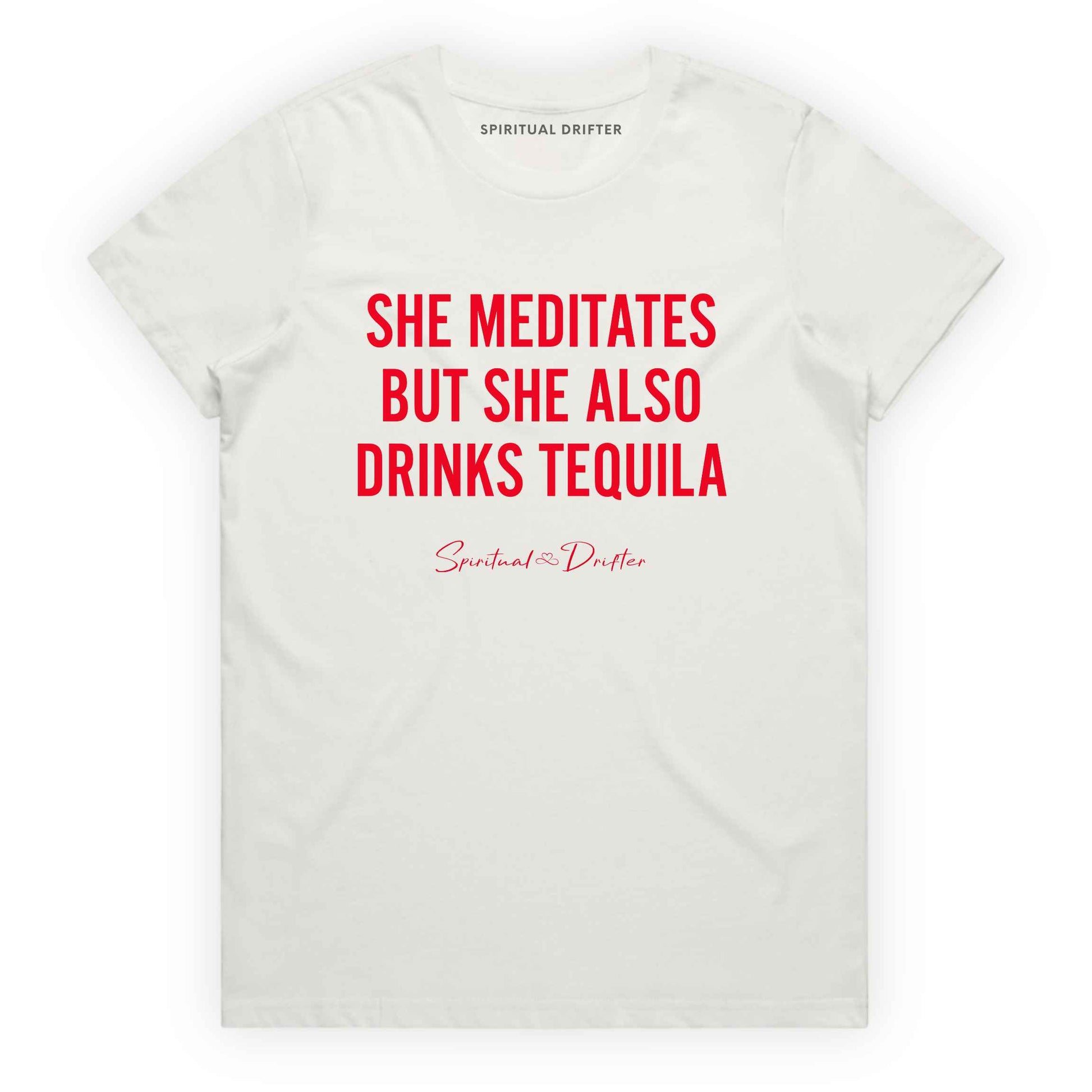 Natural Spiritual Drifter t-shirt with red text 'SHE MEDITATES BUT SHE ALSO DRINKS TEQUILA' on a white background. Women's spiritual graphic tee. Relaxed beach lifestyle fashion for meditation lovers, yoga enthusiasts, wellness travelers, and free-spirited women. Meditation and yoga clothing for awakened souls.