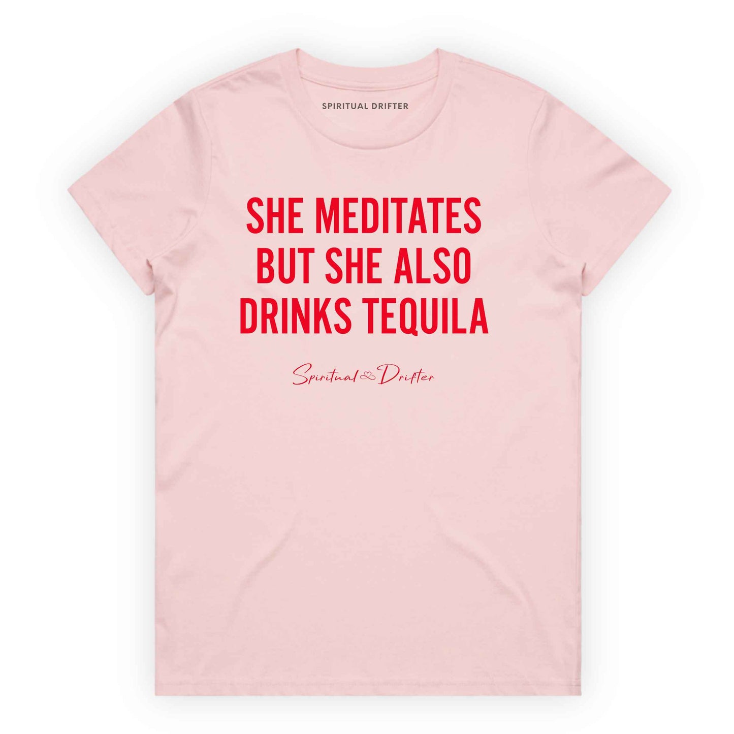 Light Pink Spiritual Drifter t-shirt with red text 'SHE MEDITATES BUT SHE ALSO DRINKS TEQUILA' on a white background. Women's spiritual graphic tee. Relaxed beach lifestyle fashion for meditation lovers, yoga enthusiasts, wellness travelers, and free-spirited women. Meditation and yoga clothing for awakened souls.