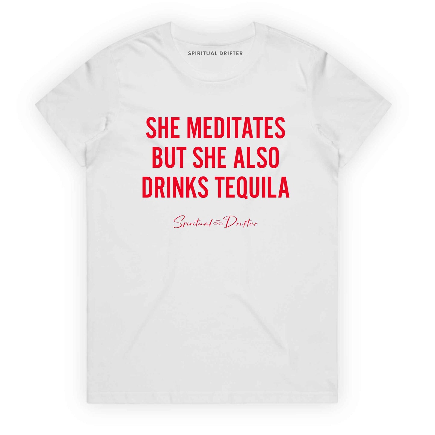 White Spiritual Drifter t-shirt with red text 'SHE MEDITATES BUT SHE ALSO DRINKS TEQUILA' on a white background. Women's spiritual graphic tee. Relaxed beach lifestyle fashion for meditation lovers, yoga enthusiasts, wellness travelers, and free-spirited women. Meditation and yoga clothing for awakened souls.