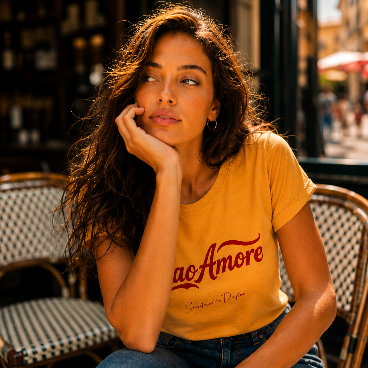 Woman wearing a mustard yellow Spiritual Drifter t-shirt with red text 'Caio Amore', sitting in a cafe in Lake Como Italy.