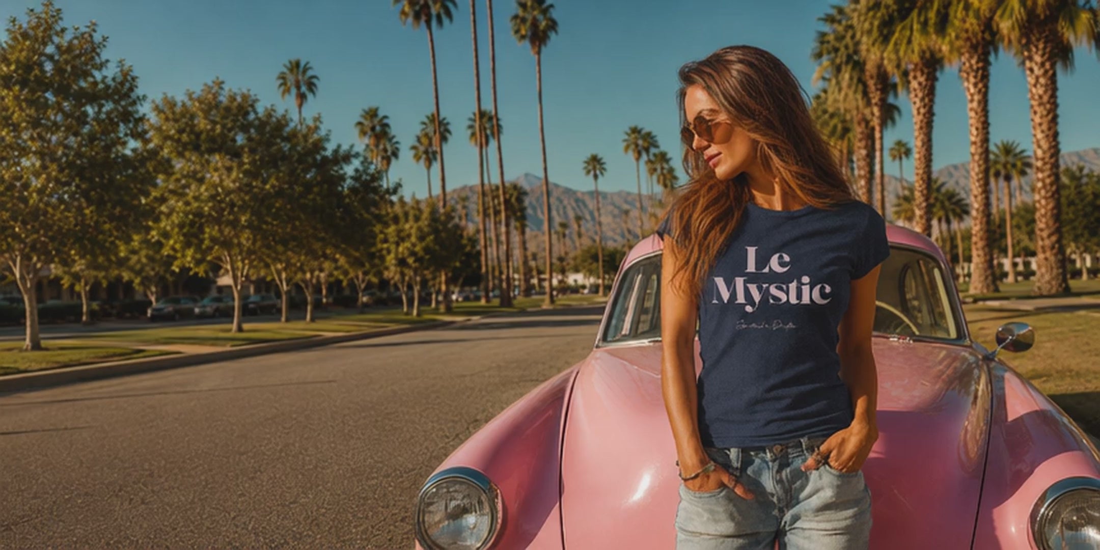 Load video: Spiritual Drifter conscious clothing home page video featuring a woman wearing the Le Mystic graphic t-shirt in Palm Springs with vintage pink car, palm trees and desert mountains. Premium women's graphic tee, minimalist spiritual apparel, conscious fashion brand, boho luxury style, retro aesthetic, elevated lifestyle clothing, mindful fashion, clothing for awakened souls, spiritual streetwear, intentional living apparel, desert resort fashion.