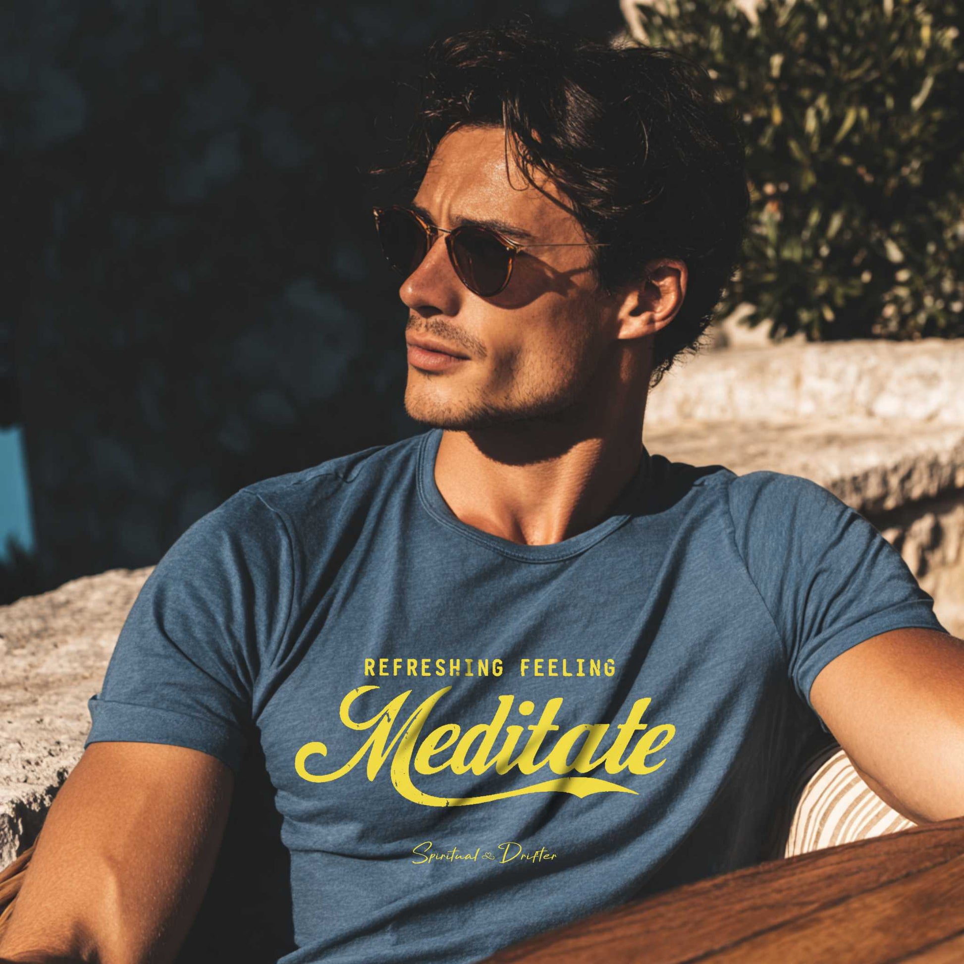 Man wearing a blue t-shirt with 'Refreshingly Feeling Meditate' text, sitting outdoors. Male Model wearing Spiritual Drifter Meditate organic t-shirt during a mindful outdoor moment – spiritual lifestyle clothing 
