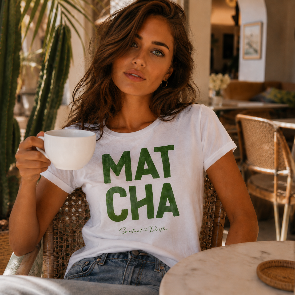 Woman wearing a Spiritual Drifter 'MATCHA' t-shirt sitting in an elegant cafe in Pal Springs holding a matcha green tea cup outdoors.
